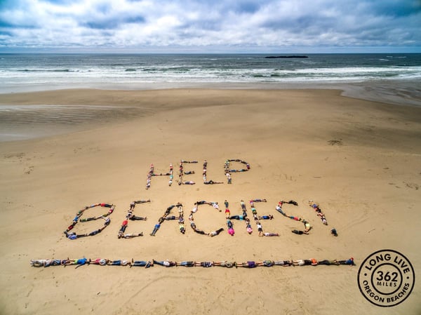 aerial image of students laying on beach that have spelled out 